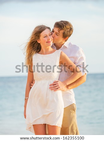 Happy romantic couple kissing on the beach at sunset, Man and woman in love