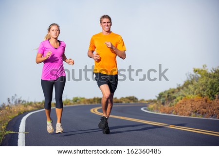 Fitness sport couple jogging outside, training together outdoors. Running on road