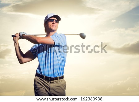 Golfer at sunset, Man swinging golf club with dramatic sunset sky backdrop