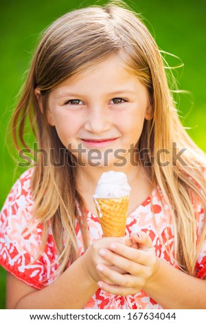 Happy cute little girl eating ice cream cone