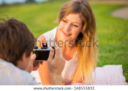 Couple taking photos of eacht other with retro vintage film camera on romantic picnic date