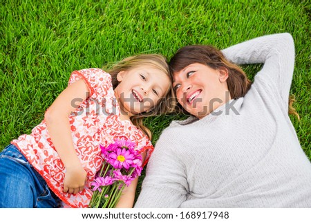 Beautiful mother and daughter lying together outside on grass, Special intimate moment