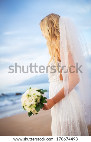 Beautiful bride in wedding dress with flowers at sunset on beautiful tropical beach in Hawaii