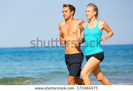 Couple running. Sport runners jogging on beach working out smiling happy. Fitness exercise concept.