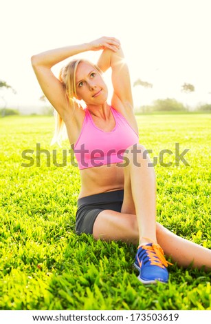 Attractive fit young woman stretching before exercise workout, sunrise early morning backlit. Healthy lifestyle sports fitness concept.