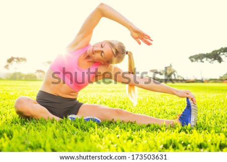 Attractive fit young woman stretching before exercise, sunrise early morning backlit. Healthy lifestyle sports fitness concept.