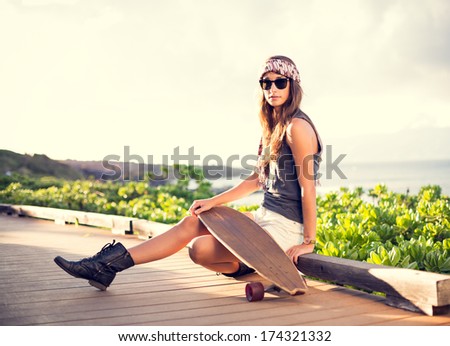 Fashion lifestyle, Beautiful young woman with skateboard, backlit at sunset