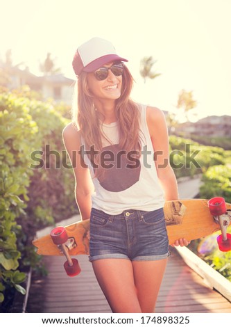 Fashion lifestyle, Beautiful young woman with skateboard, backlit at sunset