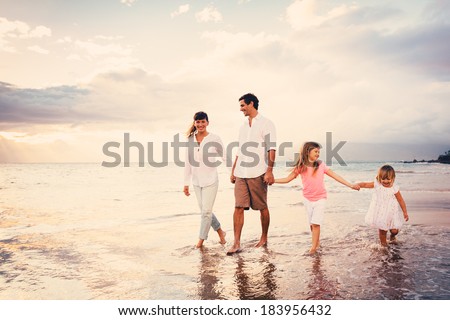 Happy Young Family Having Fun Walking on Beach at Sunset
