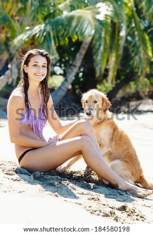 Attractive Young Woman Enjoying Sunny Day at the Beach with her Dog, Golden Retriever