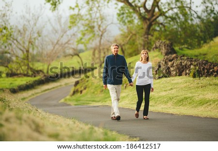 Happy loving middle aged couple walking on beautiful country road