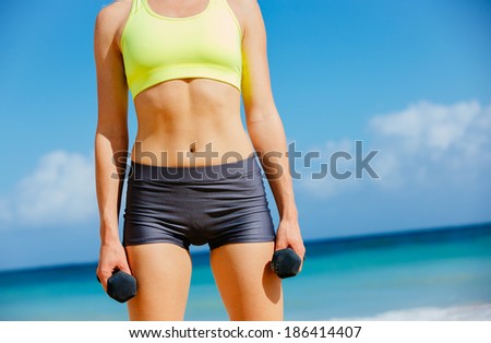 Close-up of torso of fitness woman holding barbells