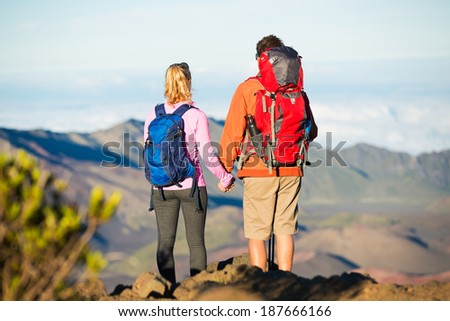 Two hikers relaxing enjoying the amazing view from the mountain top. Looking out over the volcano crater.