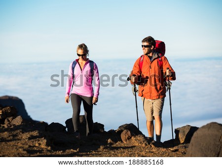 Hiking in the mountains. Happy athletic couple with backpacks enjoying hike outdoors on beautiful mountain trail.