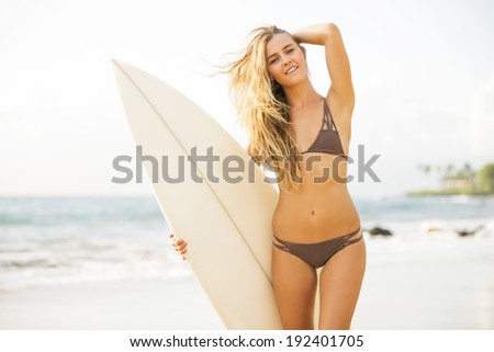 Beautiful carefree happy surfer girl on the beach at sunset. Beach culture lifestyle concept.
