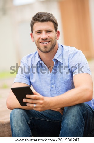 Young man reading E-book outside on steps