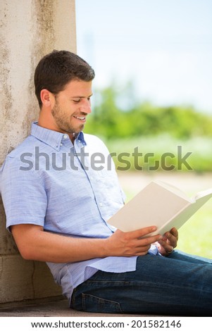 Young man reading book outside on steps