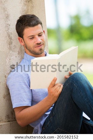 Young man reading book outside on steps