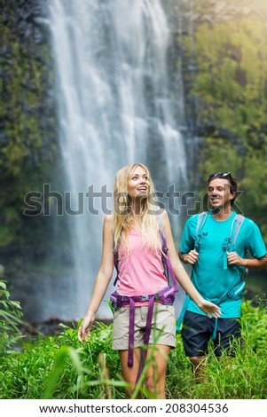 Couple having fun together outdoors on hike to amazing waterfall in Hawaii.