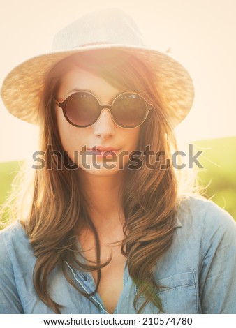 Fashion portrait of beautiful young woman in hat and sunglasses oustide, bright warm sunny color tones