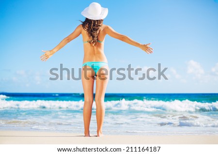 Relaxing beach vacation. Beautiful woman relaxing on sunny day at the beach. Open arms, freedom, happiness, and bliss.