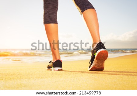 Athlete runner feet running on the beach.  Closeup on shoe and legs. Woman sunset fitness workout. Wellness healthy lifestyle concept.