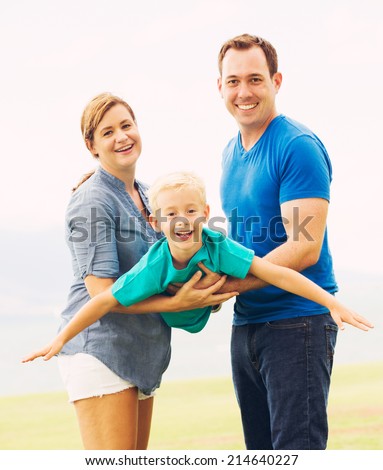 Happy Family Outside Playing Airplane with Young Son