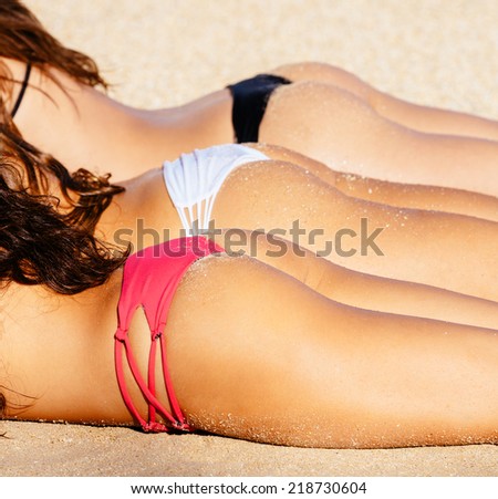 Beautiful Girls in Small Sexy Bikinis Sunbathing on the Beach. Summer fun lifestyle.