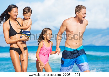 Happy Mixed Race Family of Four Playing and Having Fun on the Beach. Tropical Beach Family Vacation.