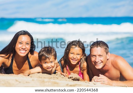 Happy Mixed Race Family of Four Playing and Having Fun on the Beach in the Sand. Tropical Beach Family Vacation.