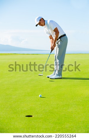 Golfer on Putting Green Hitting Golf Ball into the Hole
