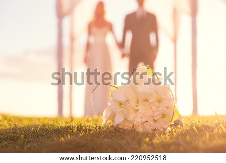 Close up of Wedding Bouquet. Focus on Flowers. Bride and Groom in Background.