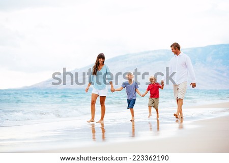 Happy Young Family Walking Down the Beach at Sunset