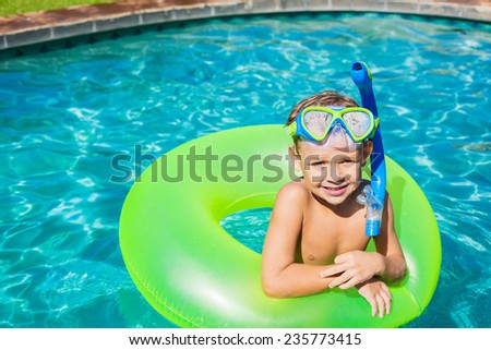 Young Kid Having Fun in the Swimming Pool On Inner Tube Raft. Summer Vacation Fun.
