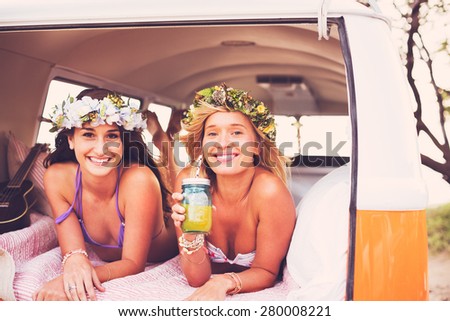 Surfer Girls Beach Lifestyle; Beautiful Surfer Girls Relaxing in the Back of Classic Vintage Surf Van on the Beach at Sunset