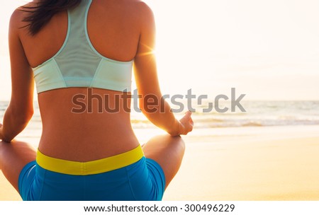 Happy young woman practicing yoga on the beach at sunset. Healthy active lifestyle concept.