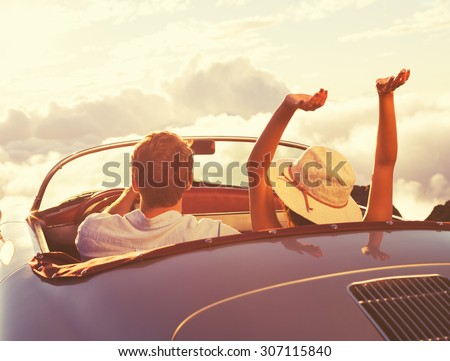 Driving into the Sunset. Happy Young Couple Enjoying the Sunset in Classic Vintage Sports Car.