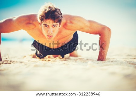Fit young man doing push-ups on beach. Outdoor beach workout. Handsome young fitness man exercising. Sports and active lifestyle fitness concept.