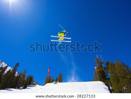 Skier goes off A Large Jump and Gets Big Air with Sun and Blue Sky