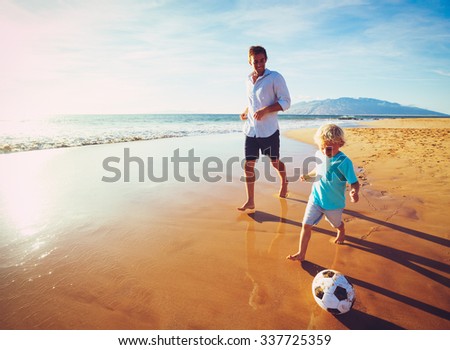 Happy Father and Son Having Fun Playing Soccer on the Beach at Sunset