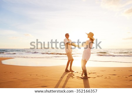 Happy Romantic Middle Aged Couple Enjoying Beautiful Sunset on the Beach. Travel Vacation Retirement Lifestyle Concept.