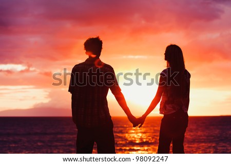 Silhouette of Young Romantic Couple Holding Hands at Sunset