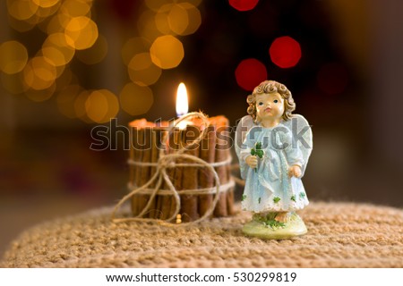 Christmas angel figurine. Handmade candles. Christmas decorations. Candle of cinnamon and bow made of jute. Bokeh.