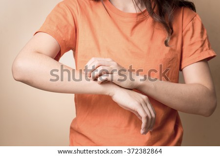 Women scratch itchy arm with hand.