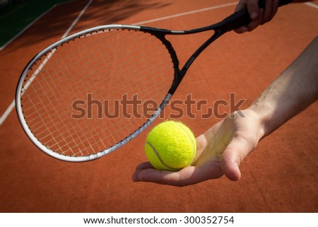 Hands holding tennis racket and ball on court
