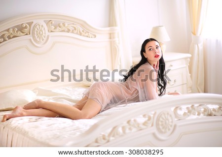 Beautiful and sexy young brunette woman in sleep dress on sofa