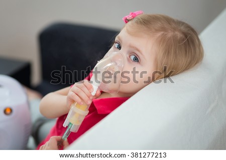 little blonde girl of three - four years is ill, is treated with a nebulizer, cough