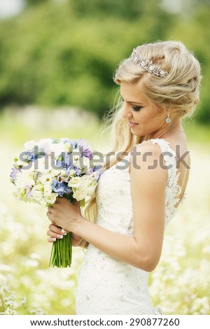 Wedding bridal bouquet in her delicate hands. Bride standing in a field