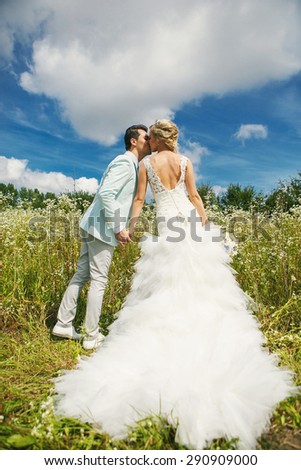 Very beautiful bride and groom kissing in a field where many colors and beautiful nature