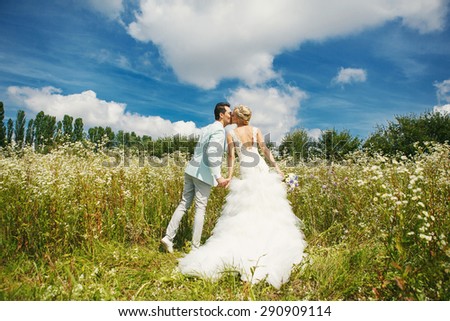 Very beautiful bride and groom kissing in a field where many colors and beautiful nature
